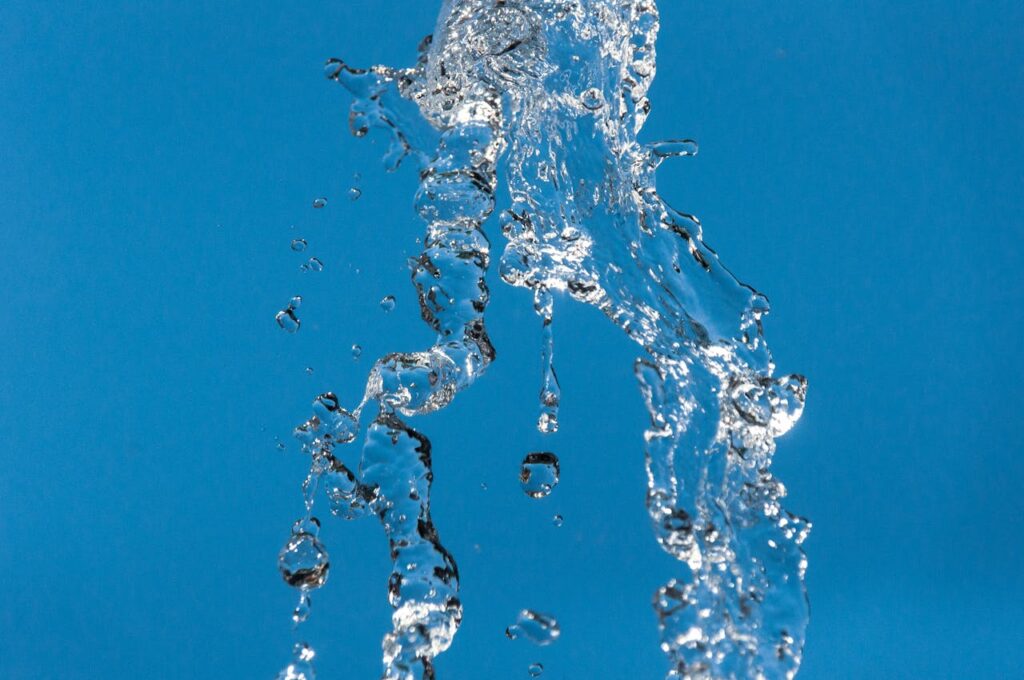 A dynamic splash of clear water captured against a vibrant blue background, conveying freshness.