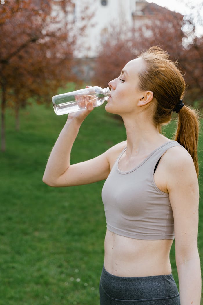 services-04 Fit woman in activewear drinking water outdoors, promoting health and wellness.